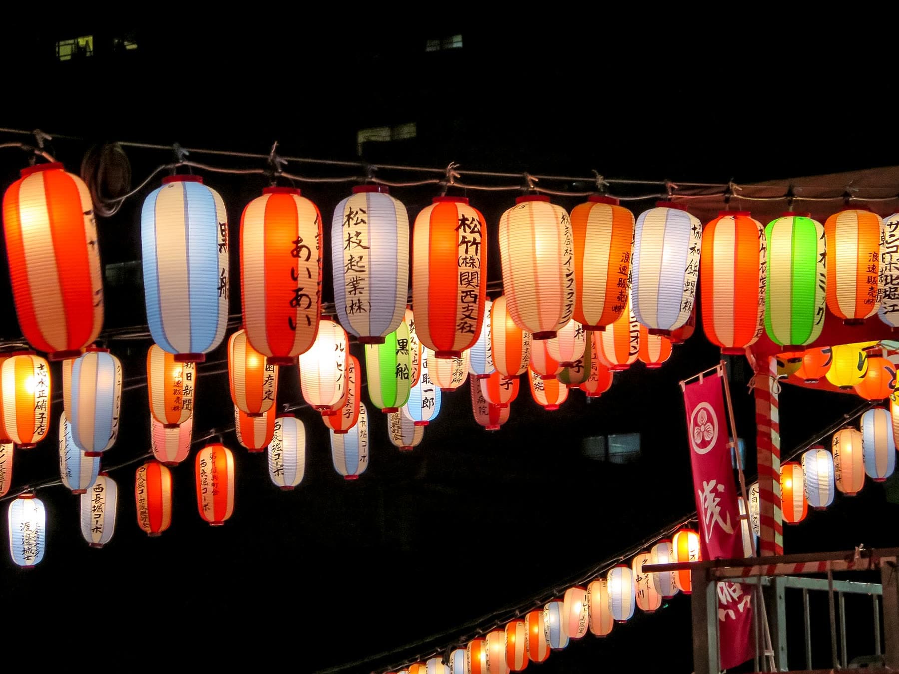 Colourful paper lanterns strung above a Bon Odori festival at night